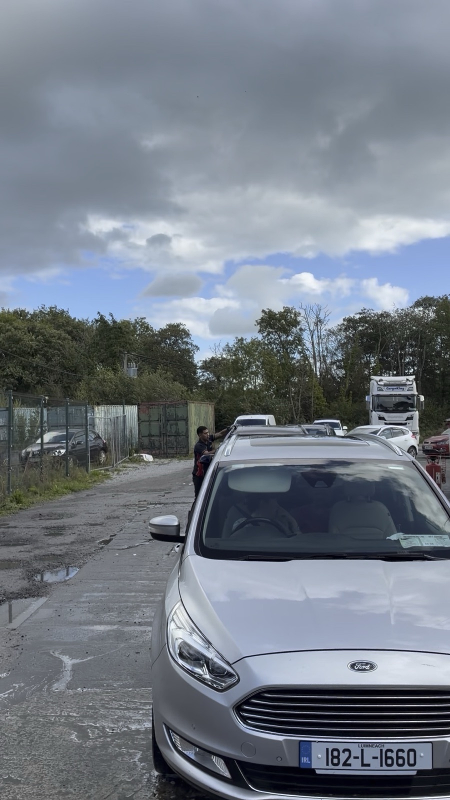 A silver Ford Galaxy parked on the wet car-wash forecourt