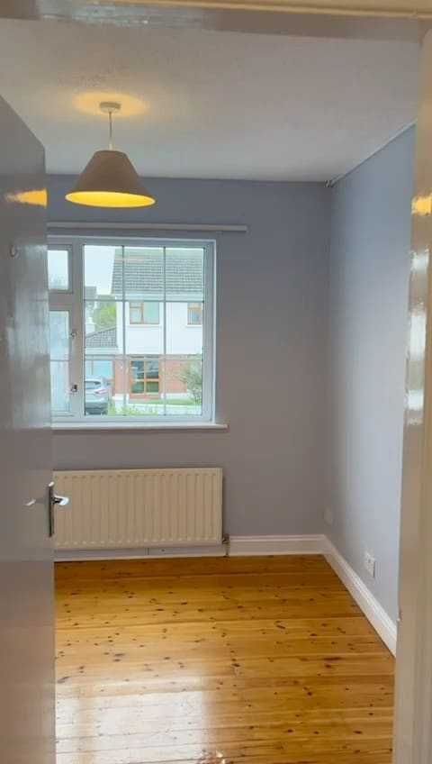 A freshly painted room with a window, radiator and timber floor