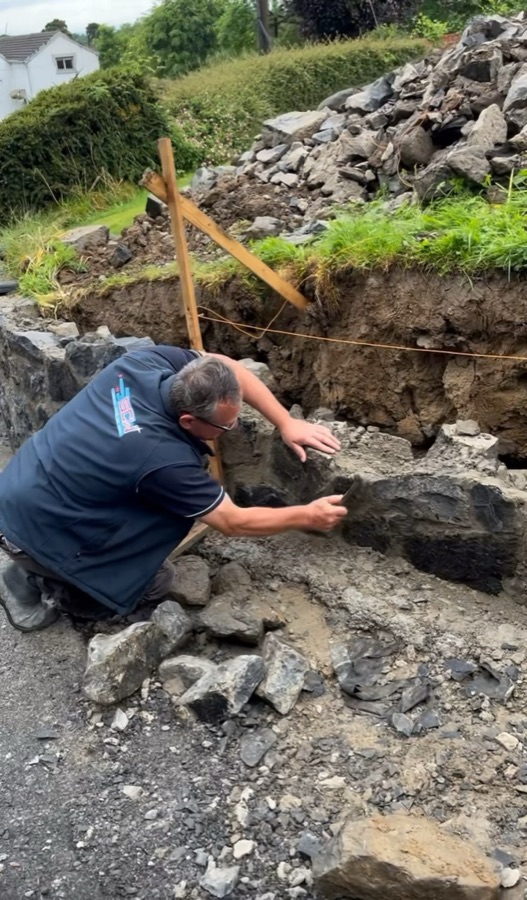 A large stone being set into a wall by hand