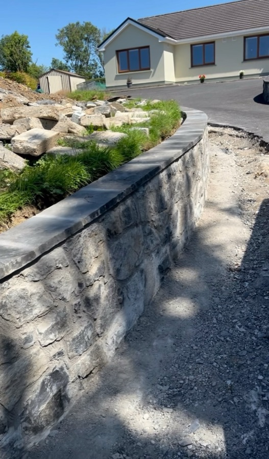 A finished curved stone boundary wall with a level coping